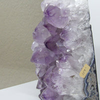 Close-up of amethyst geode face showing layered quartz and purple crystal formations, metaphysical decor for meditation spaces.