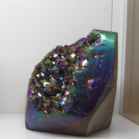 Aura quartz crystal cluster on a white surface - side