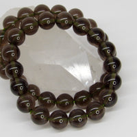 High-quality Indonesian Tektite (Agni Manitite) bracelet featuring natural 10–11mm translucent smoky olive-brown gemstone beads.