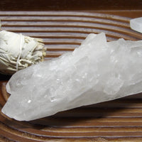 Large semi-polished clear quartz point with natural inclusions on wooden display