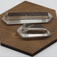 Two polished double-terminated phantom quartz points on a wooden display, 2 and 3 inches in size.