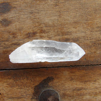 Clear quartz crystal point on a wooden surface