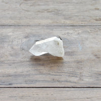 clear quartz point with milky bottom on wooden table