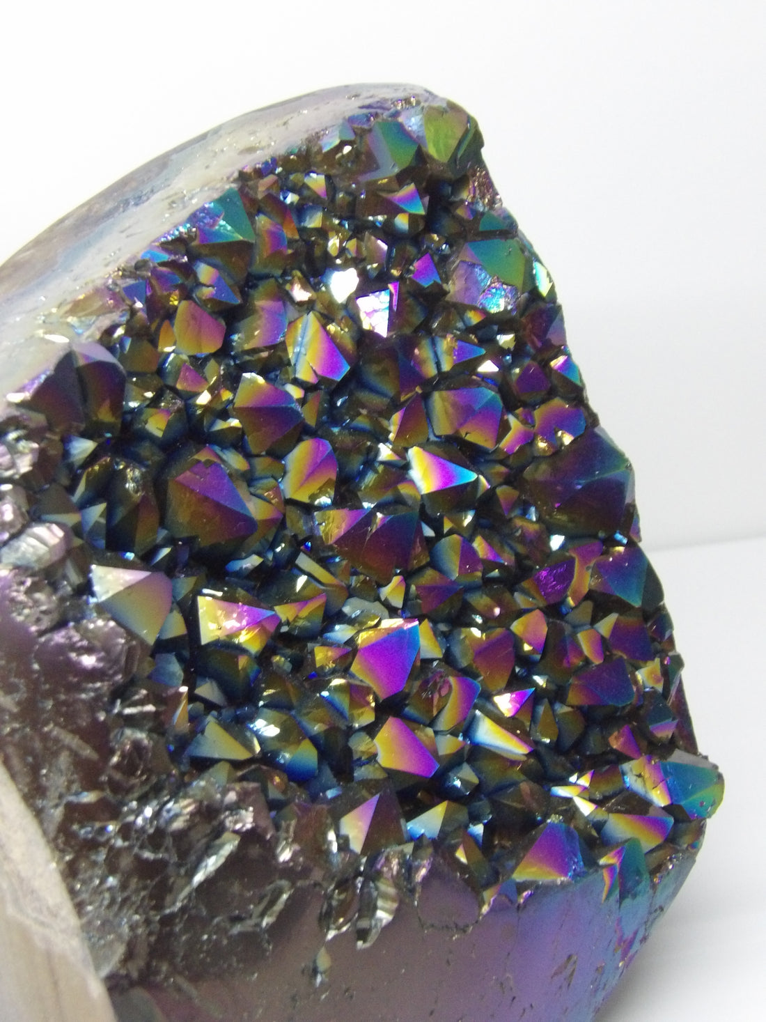 Close-up of a aura quartz crystal with iridescent colors on a white background