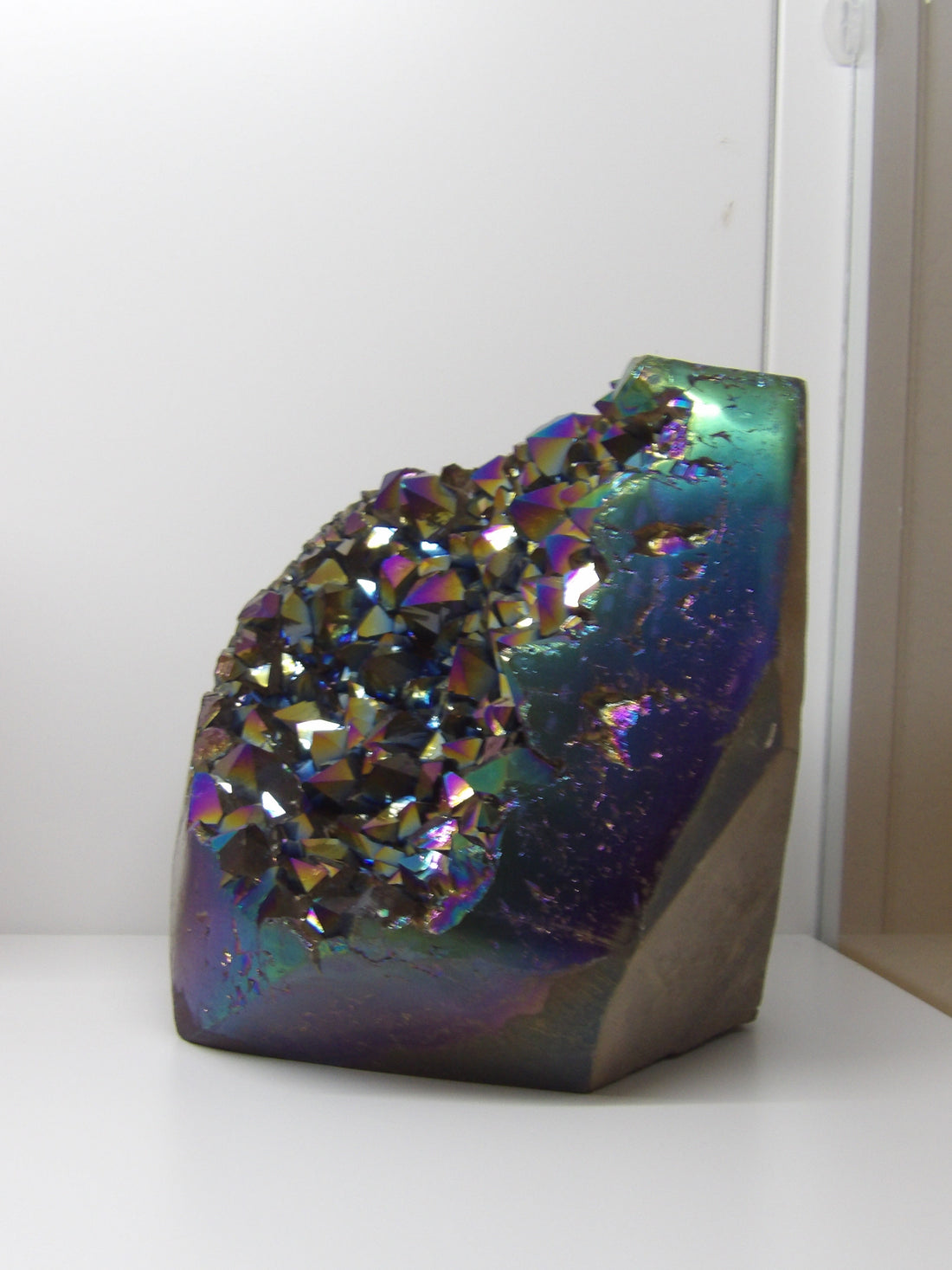 Aura quartz crystal cluster on a white surface - side