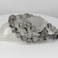 High-quality 10–11mm Tourmalinated Quartz bracelet featuring natural clear quartz beads with striking black tourmaline inclusions on a stretch cord.