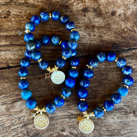 Royal blue Lapis Lazuli bracelets with gold lotus charm displayed on selenite star