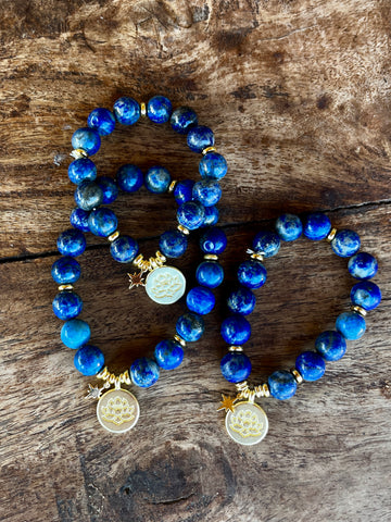 Royal blue Lapis Lazuli bracelets with gold lotus charm displayed on selenite star