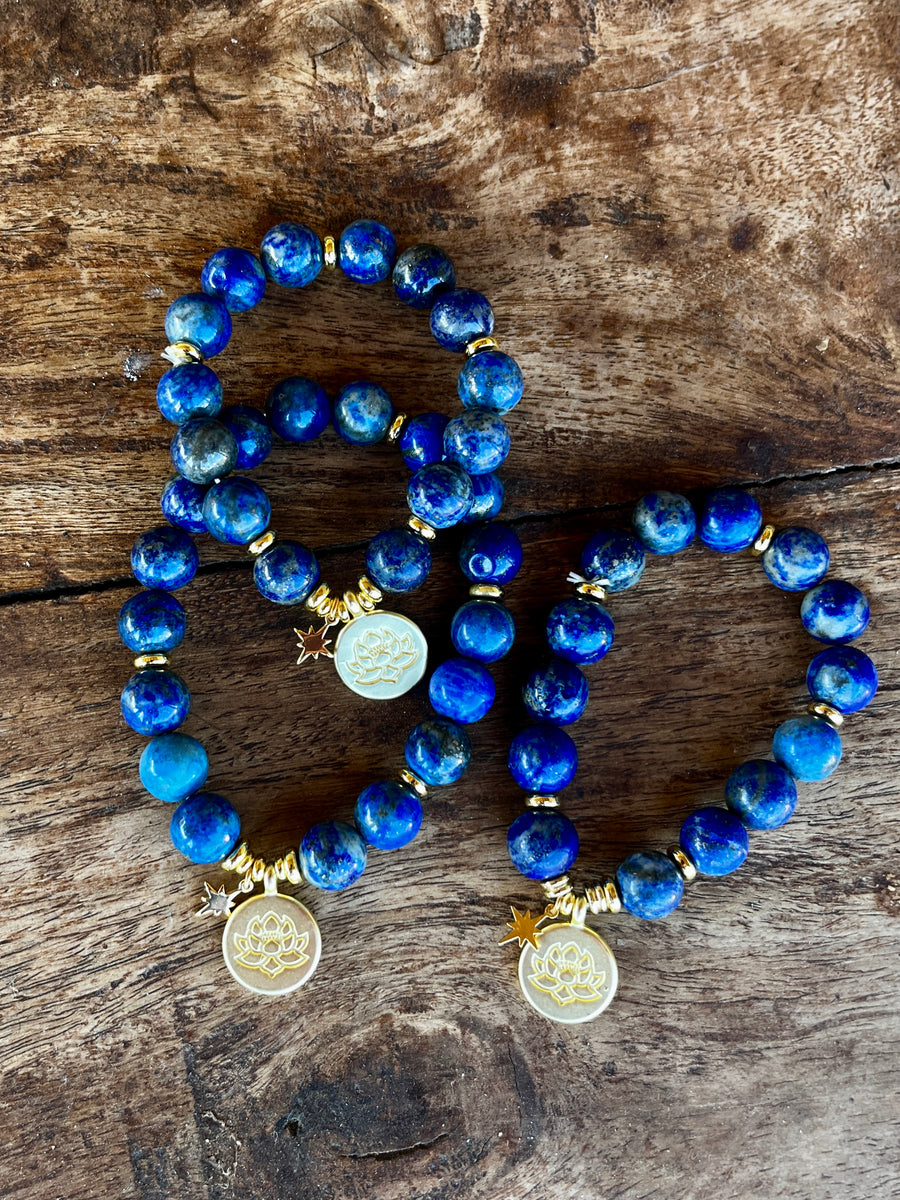 Royal blue Lapis Lazuli bracelets with gold lotus charm displayed on selenite star