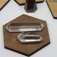 Two polished double-terminated phantom quartz points on a wooden display, 2 and 3 inches in size.