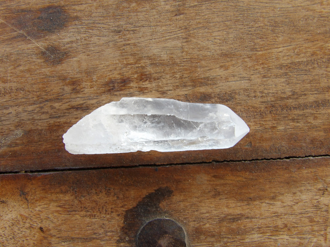 Clear quartz crystal point on a wooden surface