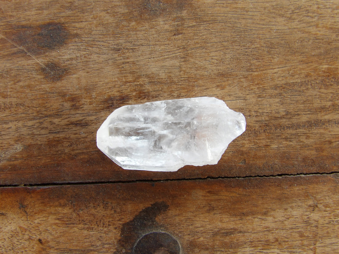 Tabular clear quartz point on wooden surface