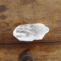 Tabular clear quartz point on wooden surface