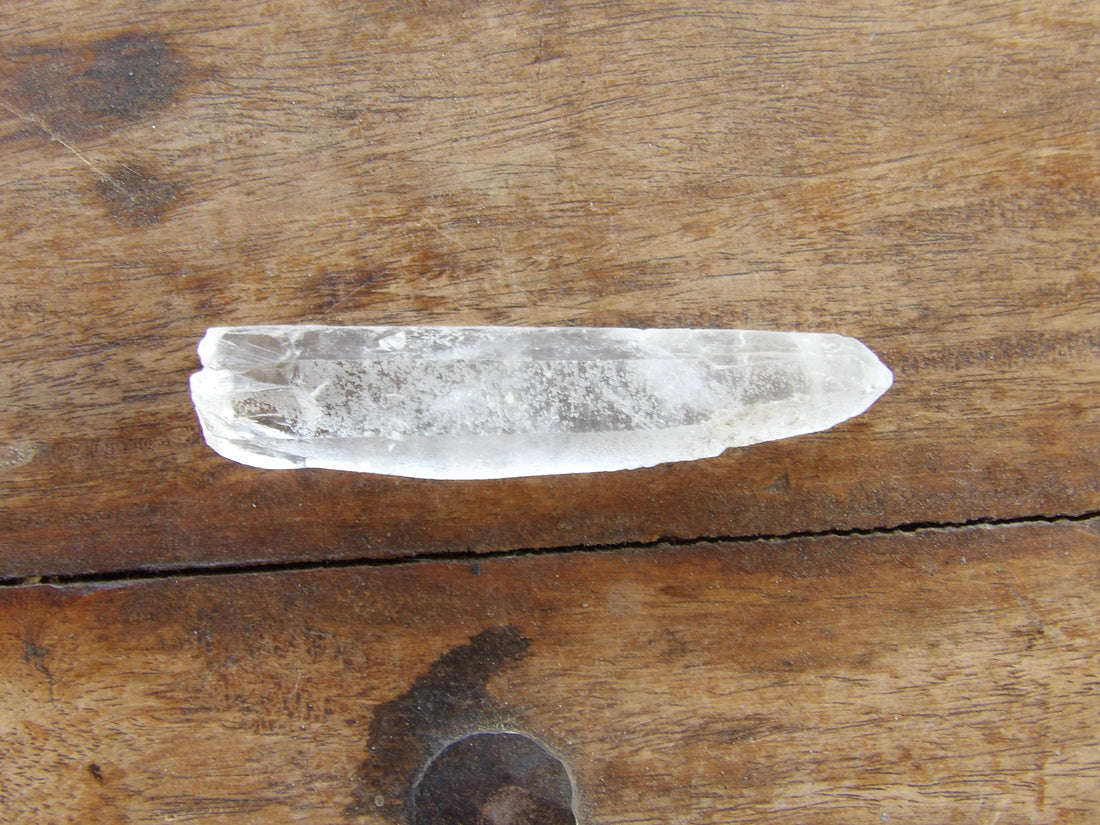 Natural clear quartz point on wooden table