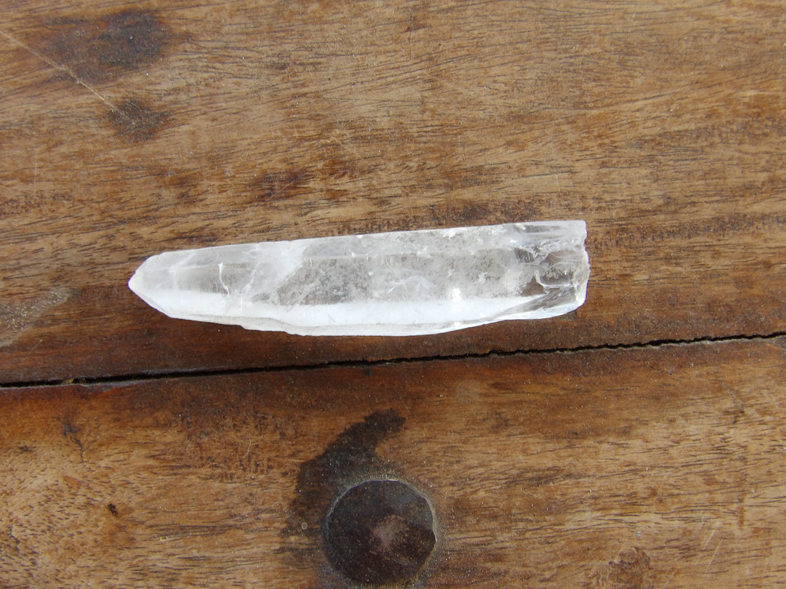Long clear quartz point on wooden surface
