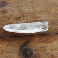 Long clear quartz point on wooden surface