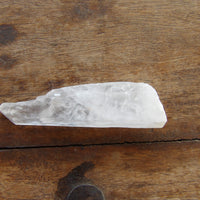 Clear quartz Crystal wand on wooden table
