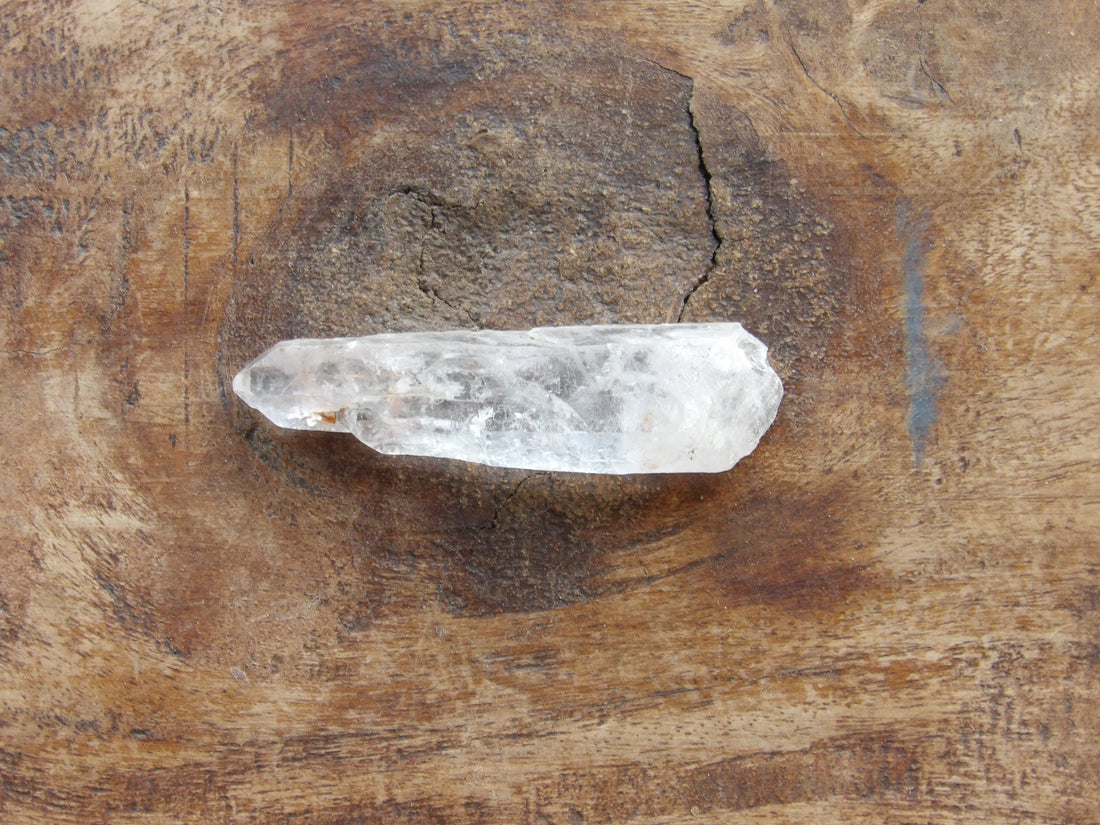 Natural included quartz point on wooden surface