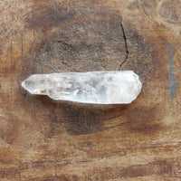 Natural included quartz point on wooden surface