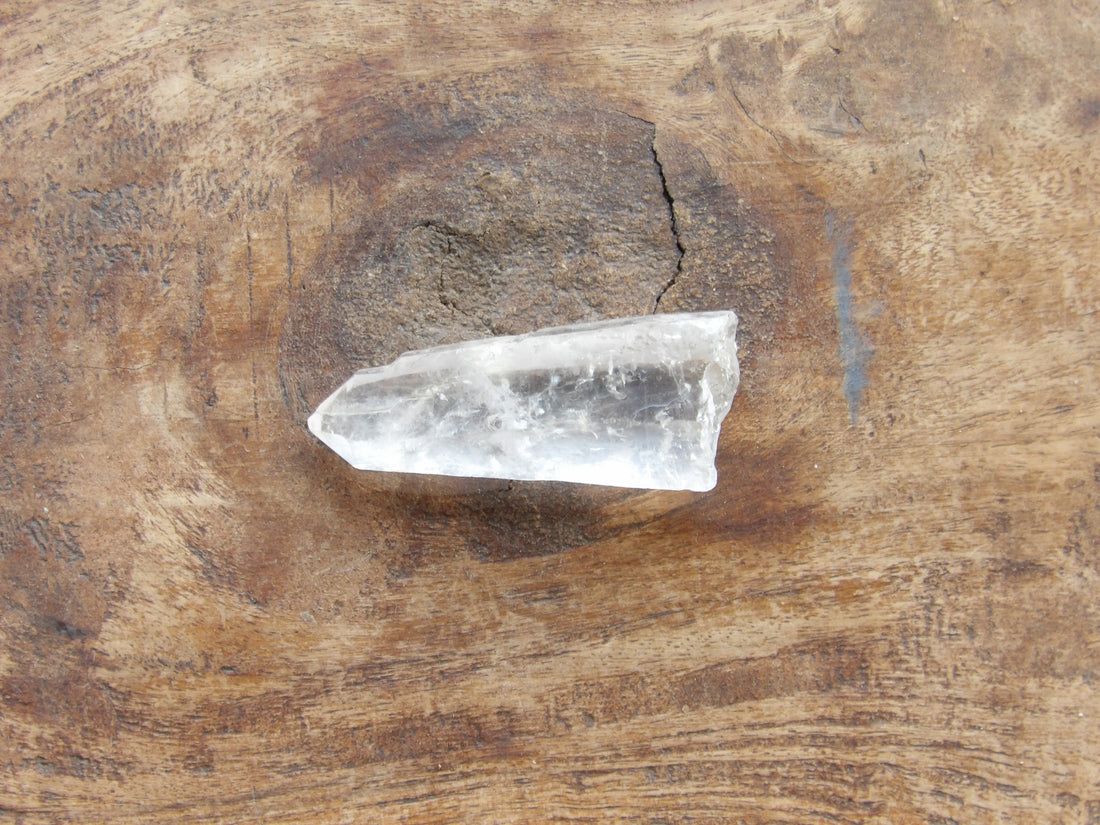 Clear crystal point on a wooden surface