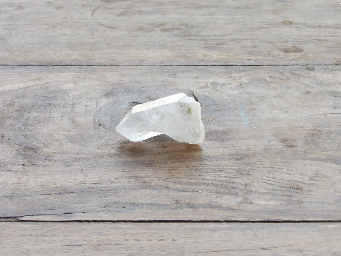 clear quartz point with milky bottom on wooden table