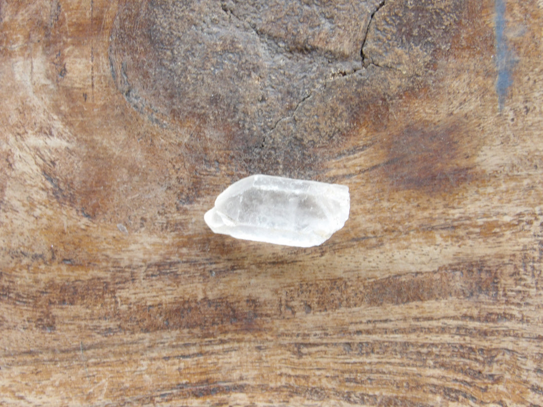 Clear quartz crystal on a textured brown surface