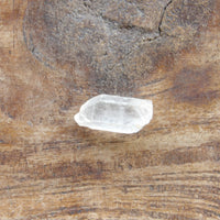 Clear quartz crystal on a textured brown surface