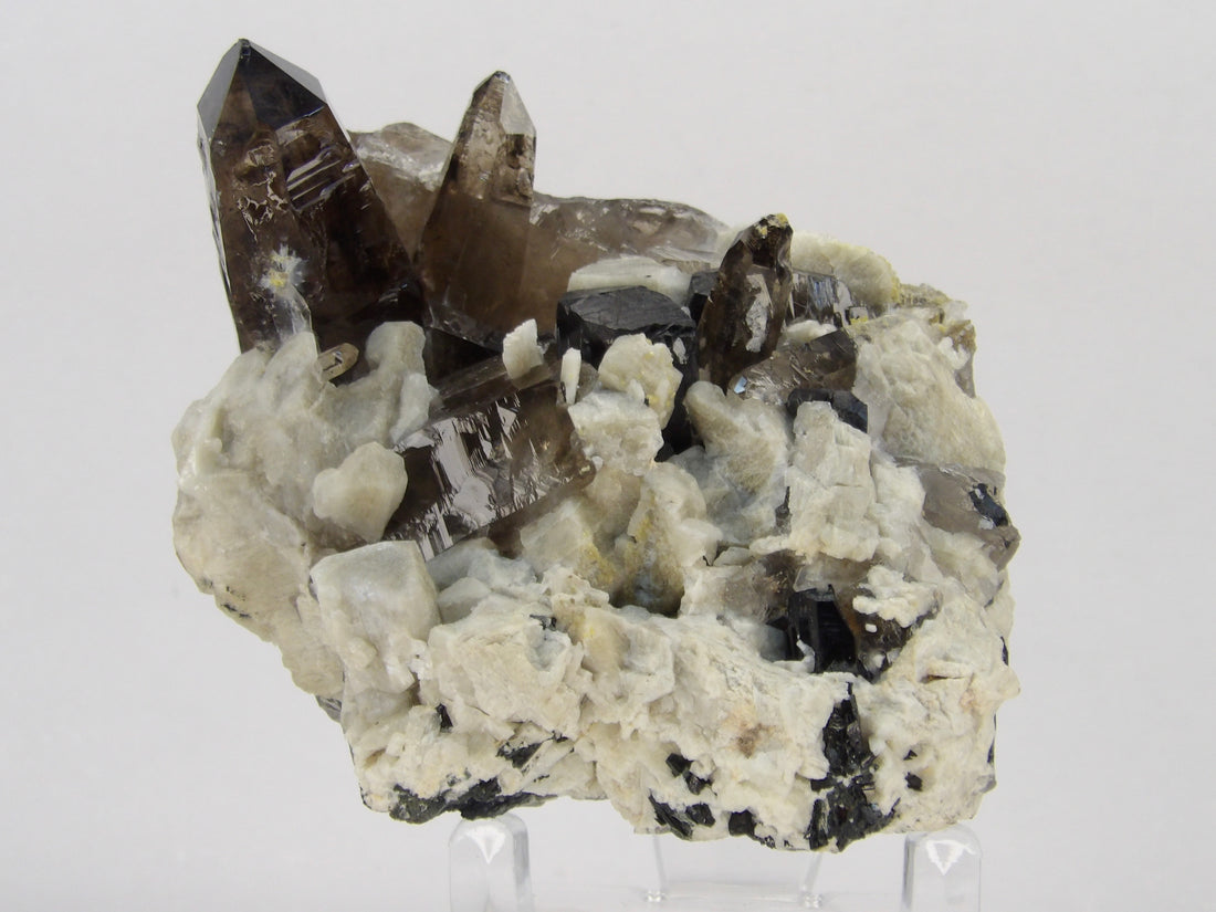 lustrous smoky quartz crystals rising from a contrasting white matrix accented with naturally occurring black aegirine crystals from Malawi.