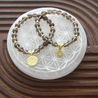Smoky quartz grounding bracelet with 18k gold-plated lotus charm and gold spacers, limited edition.