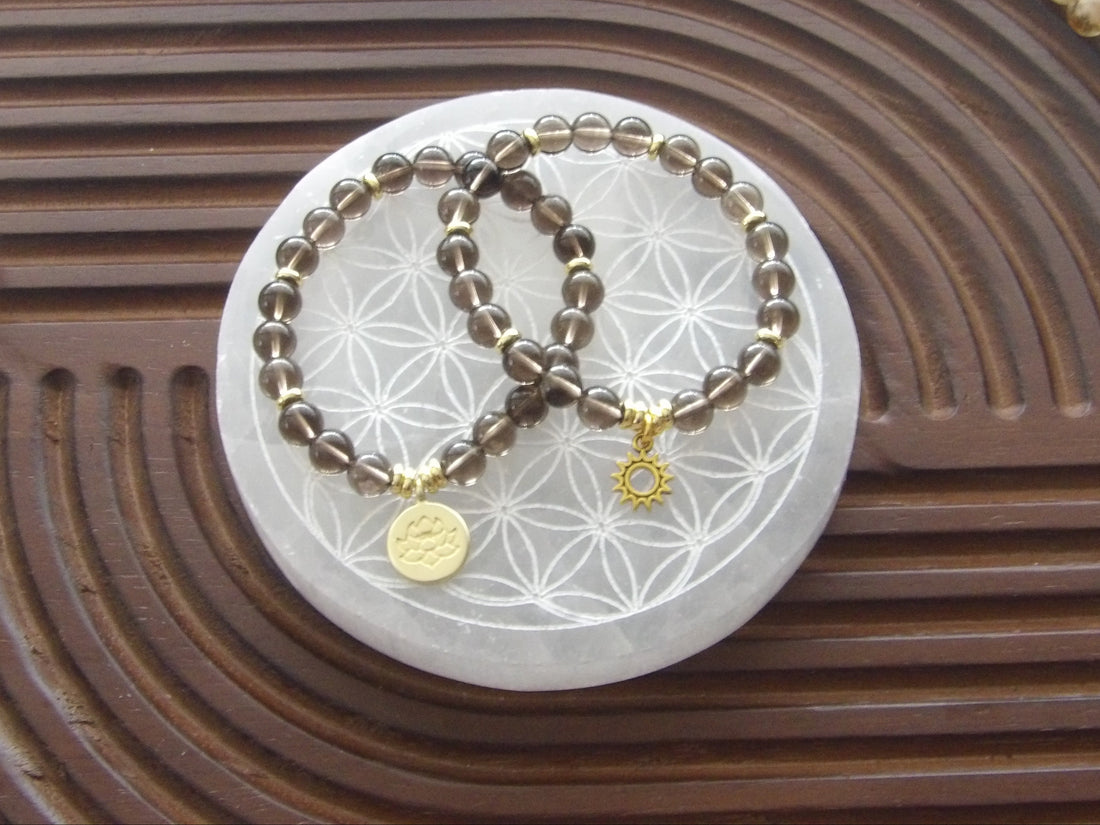 Smoky quartz bracelet featuring 18k gold-plated lotus charm and gold spacers; sun charm shown is gold-tone.