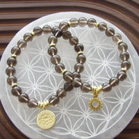 Natural smoky quartz bracelet with gold-plated lotus charm for protection and grounding energy.