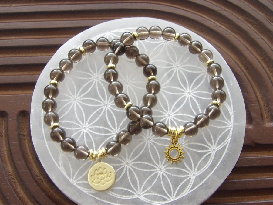 Natural smoky quartz bracelet with gold-plated lotus charm for protection and grounding energy.